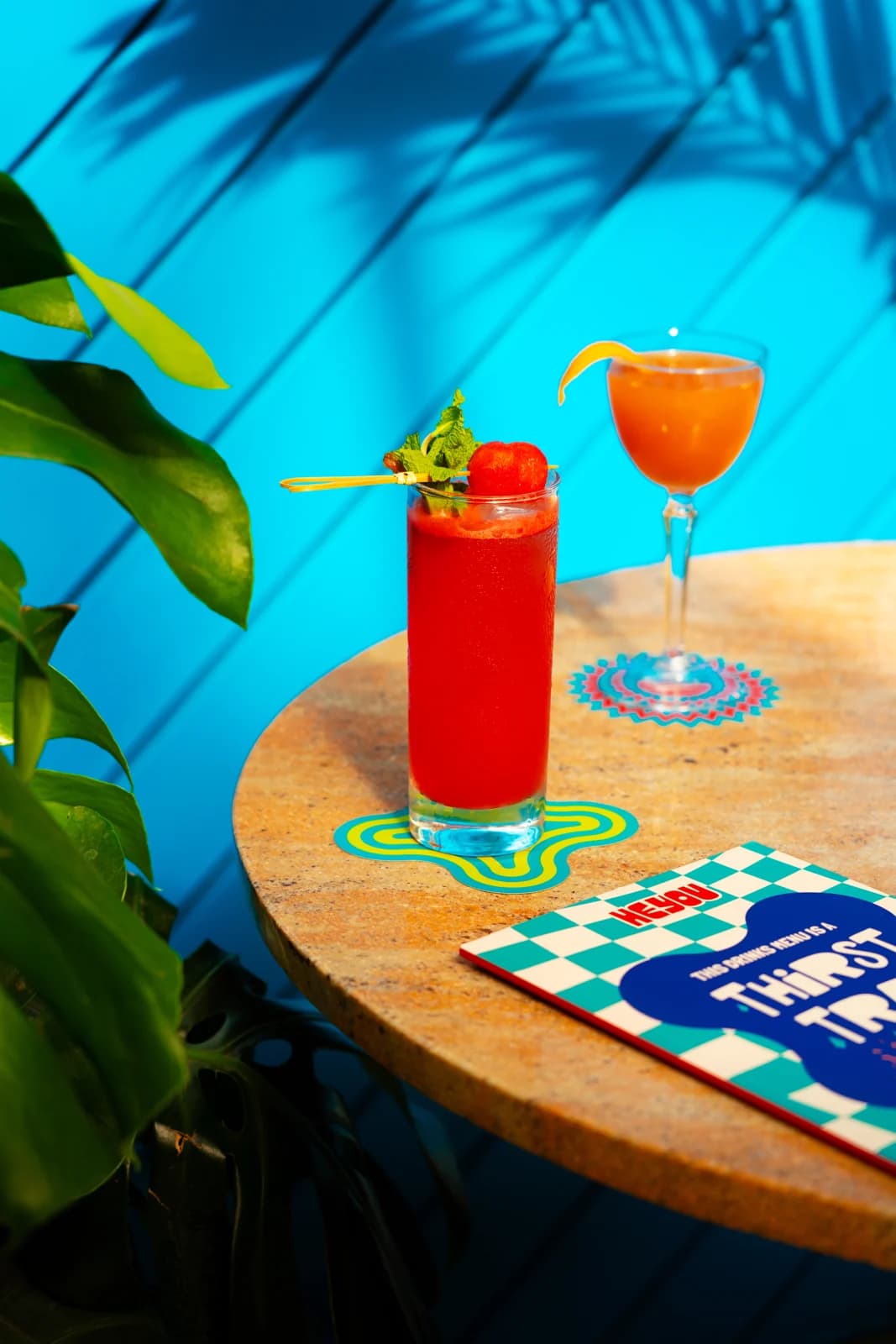 Red Room and Slow Burn cocktails against Heyou's blue wall