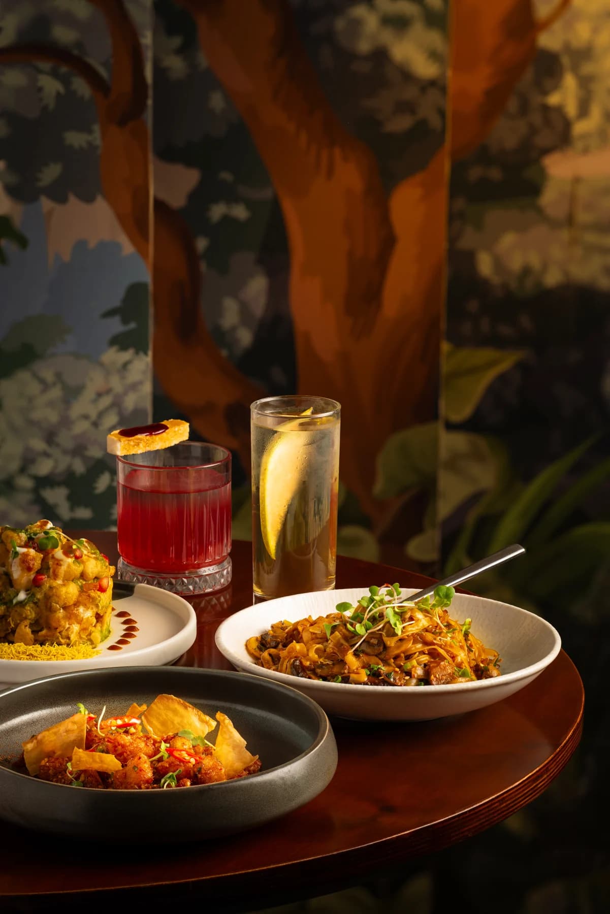 Heyou plates and signature cocktails against the restaurant’s patterned walls